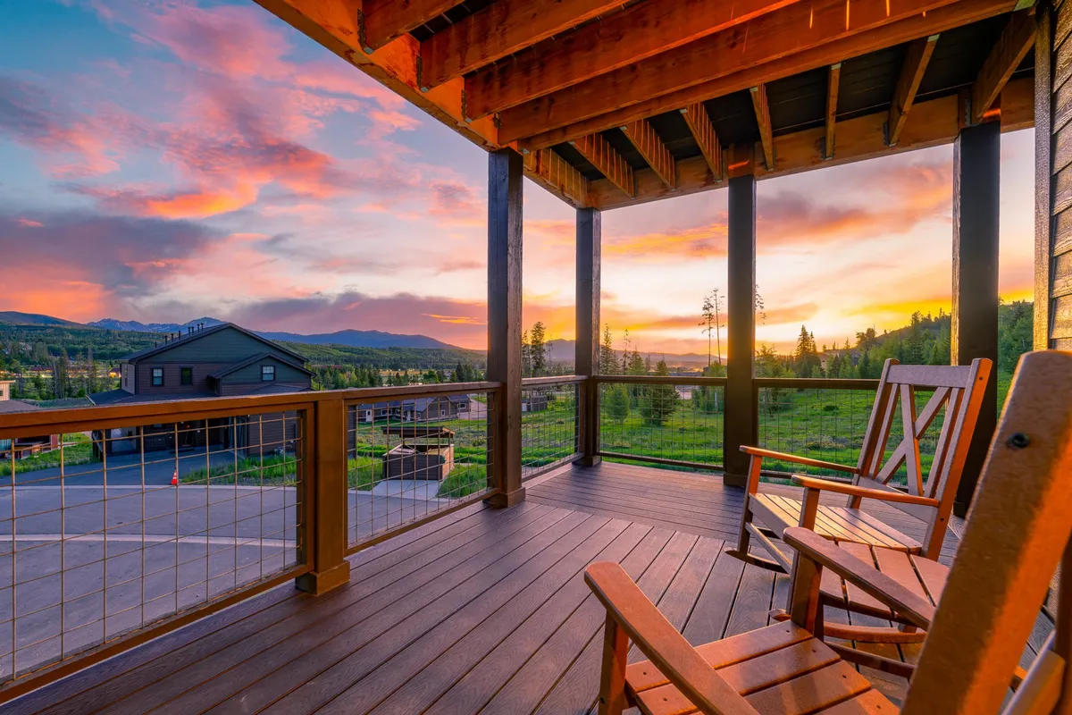 An inviting exterior shot showing two rocking chairs set against a backdrop of mountain views and a colorful sunset sky. The setting conveys relaxation and opportunities for socializing in a scenic, tranquil environment.