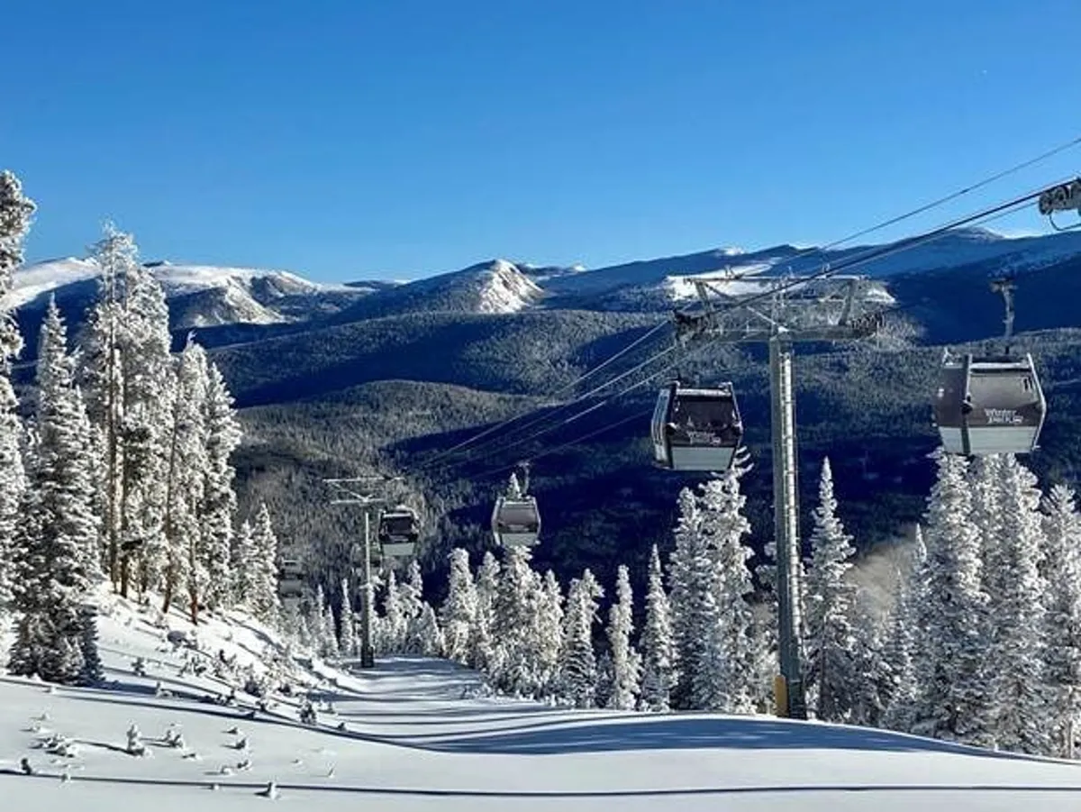A sweeping exterior scene of a gondola lift gliding over snow-covered trees, with an expansive mountain range in the background—capturing the thrill of winter sports and the beauty of the Rocky Mountains.